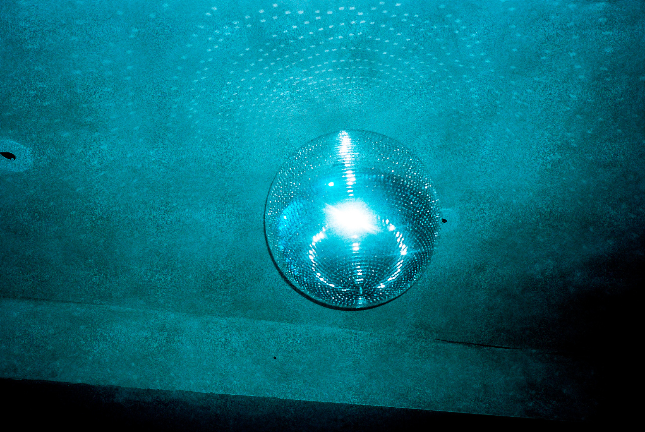 A mirrorball spinning under blue light in a dark room