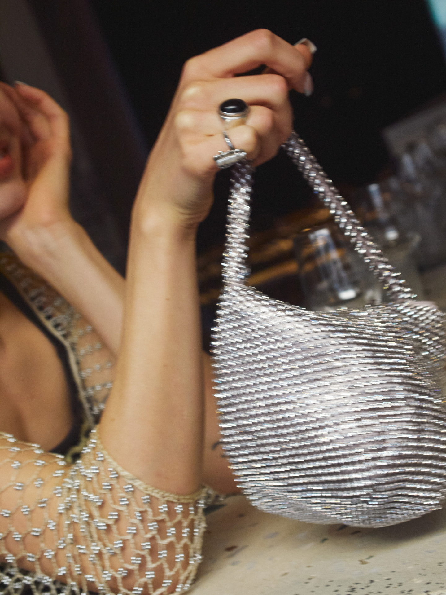 A guest holding a beaded silver evening bag at a party